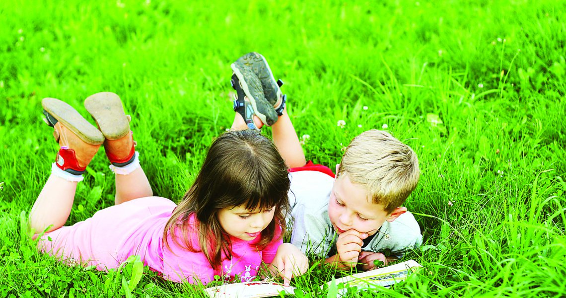 bigstock-Kids-reading-a-book-on-grass-16555607